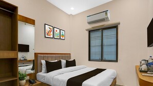 Een hotelkamer met een bed, nachtkastje, spiegel, raam en airconditioning.