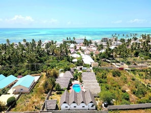 A coastal village with thatched-roof houses, a swimming pool, and a view of the ocean. - Mkeka Spice Lodge Jambian (Unguja South Region)