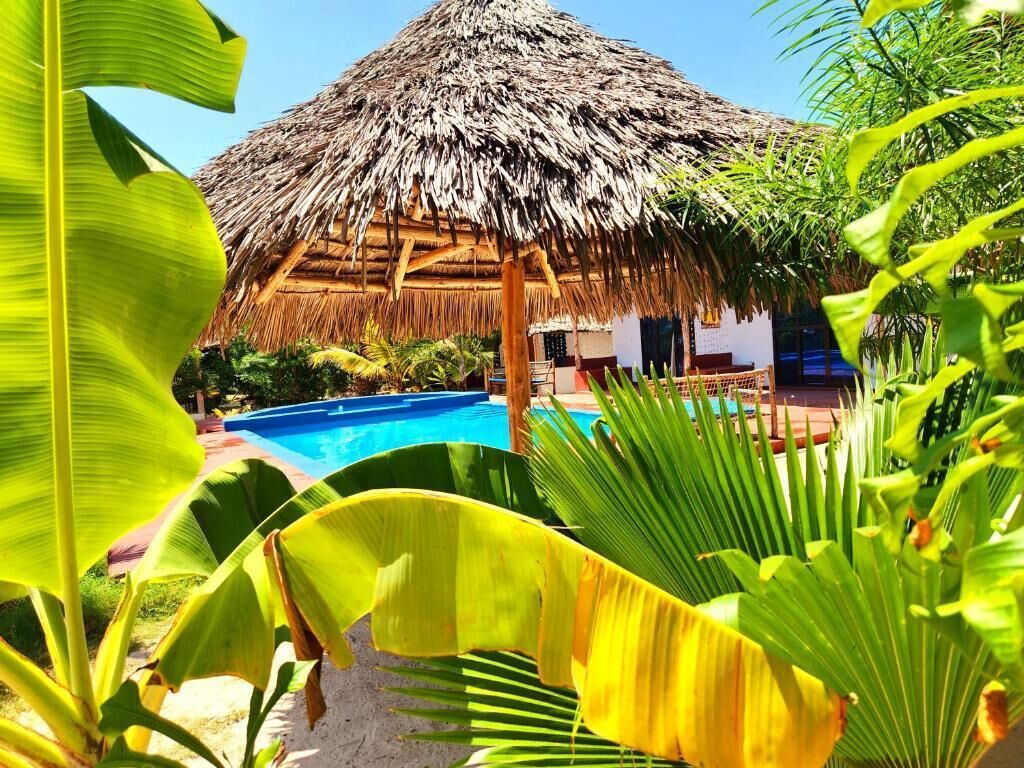 Ein Häuschen mit einem Pool und üppiger tropischer Vegetation.
