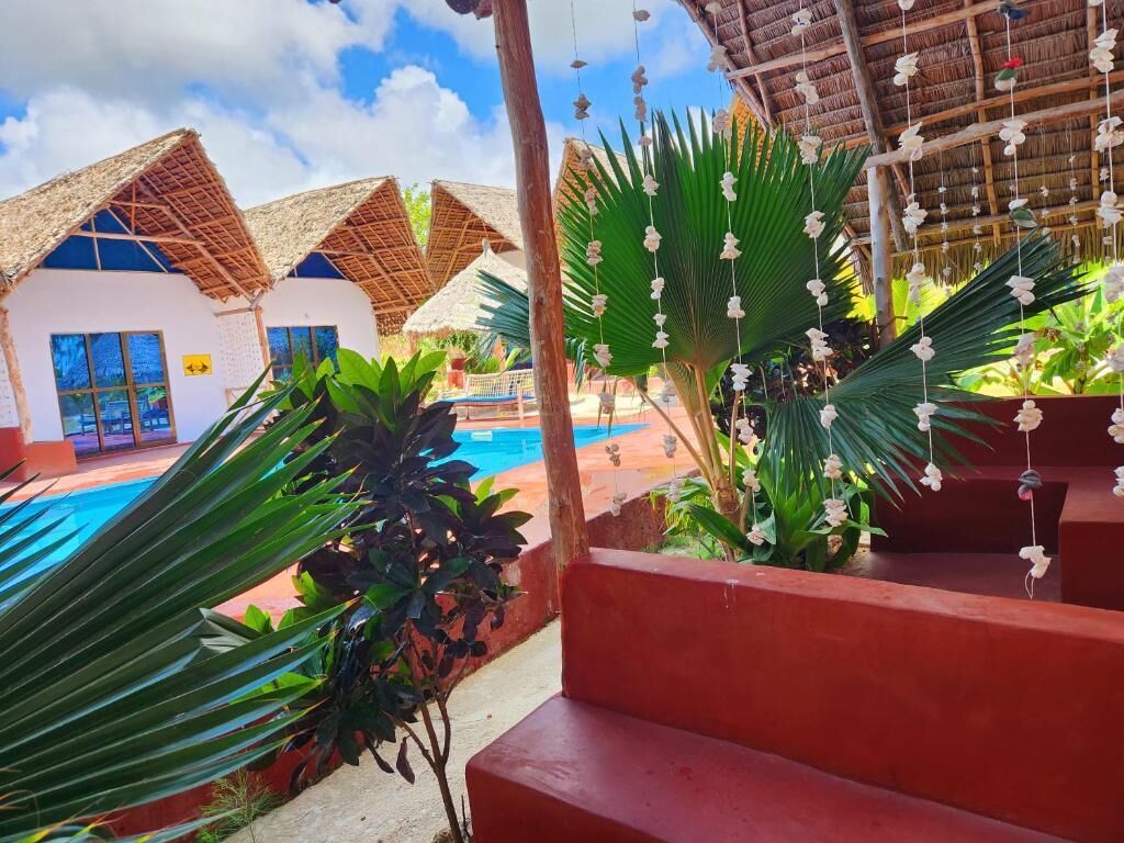 A resort with thatched-roof structures, a swimming pool, and tropical plants.
