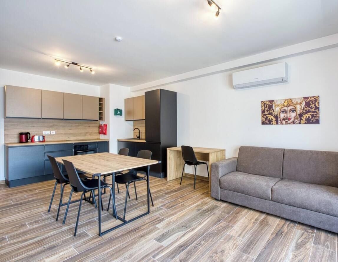 A modern kitchen with a dining area, a sofa, and a painting on the wall.