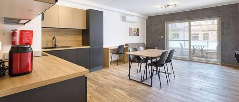 A modern kitchen with a wooden countertop, a dining area with a table and chairs, and a large sliding glass door leading to an outdoor balcony.