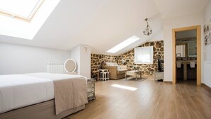 A bedroom with a skylight, a bed, a small desk, a chair, and a stone wall. - Room-rural House Santervas de la Sierra (Garray)