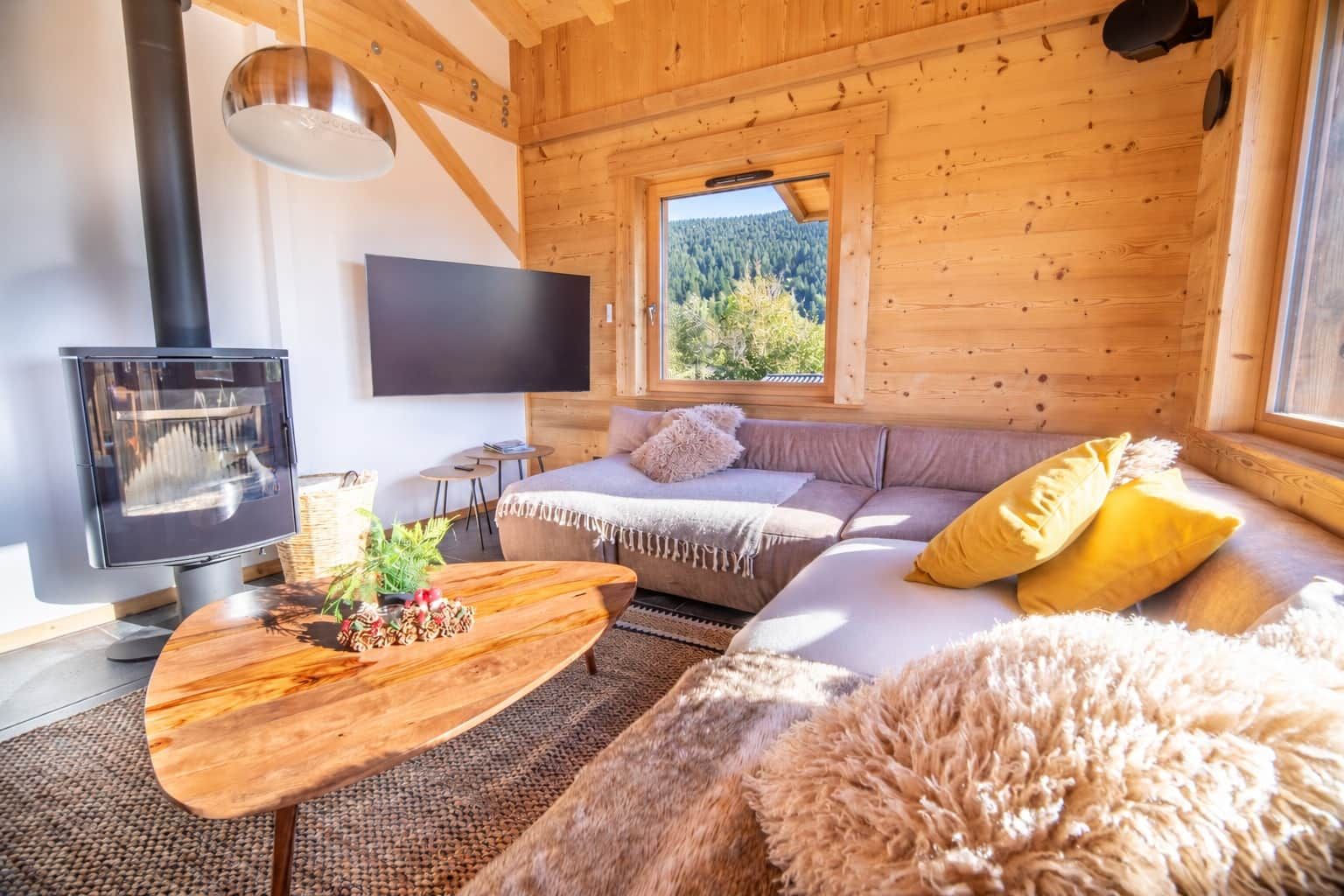 A cozy cabin interior with a sofa, a flat-screen TV, and a fireplace.