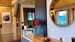 A reception area with a wooden reception desk, a round mirror, and a view of the outdoors. - Ma Biche: a beautiful chalet with a lake view and a Nordic hot tub! (Gérardmer)