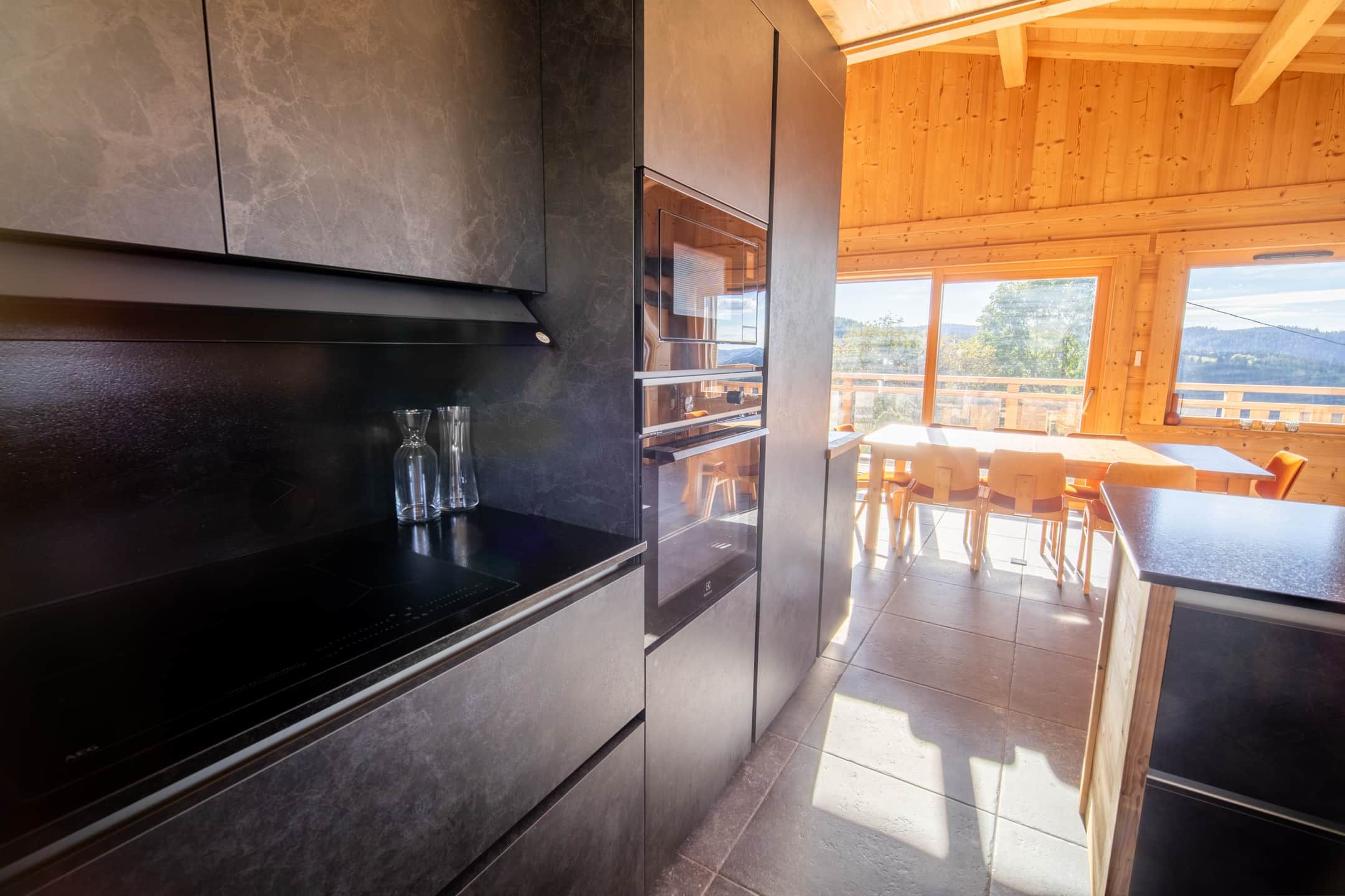 A modern kitchen with a built-in oven and a dining area with a view of the outdoors.