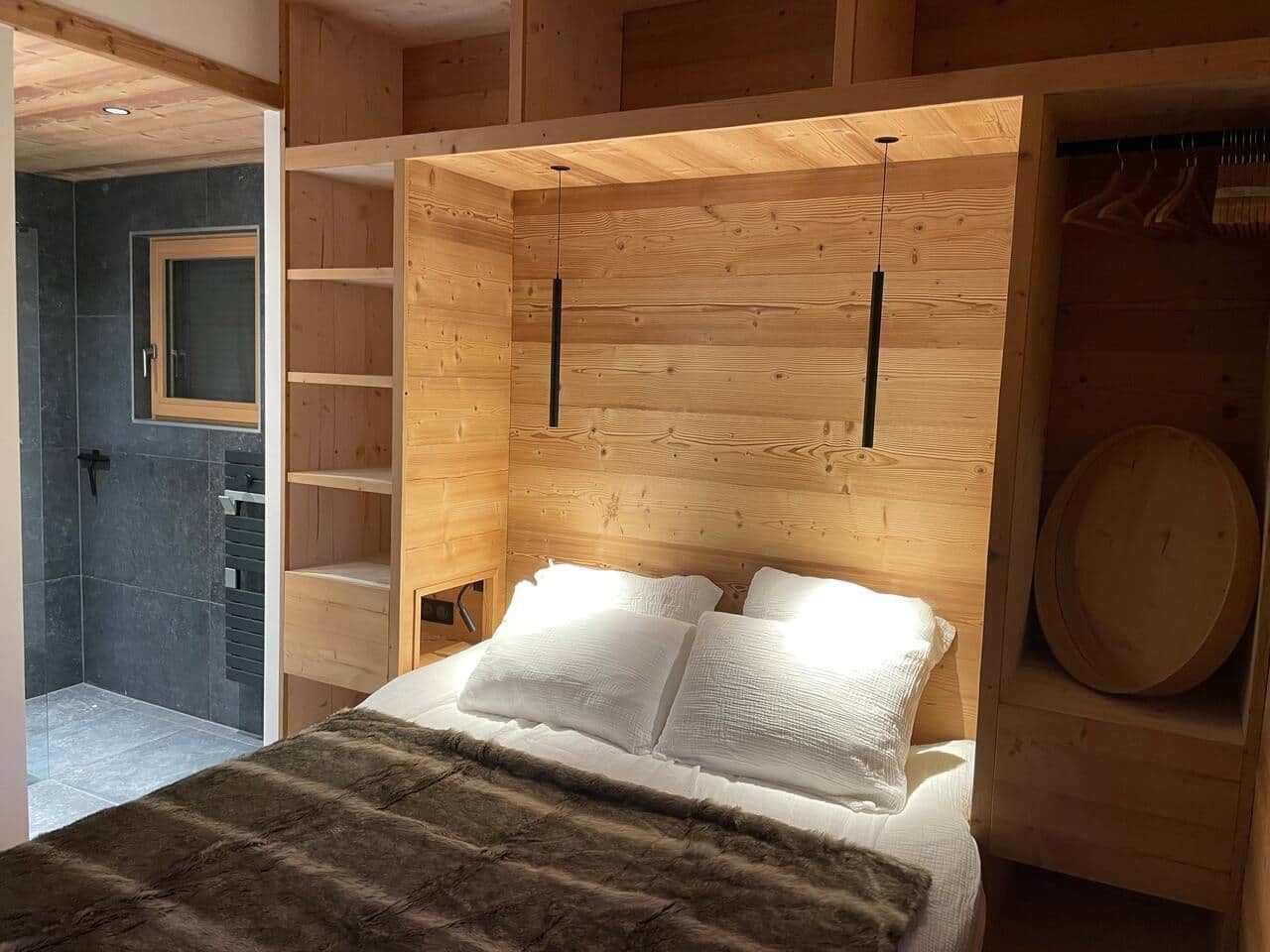 A wooden bedroom with a bed, a shelf, and a circular object on the wall.