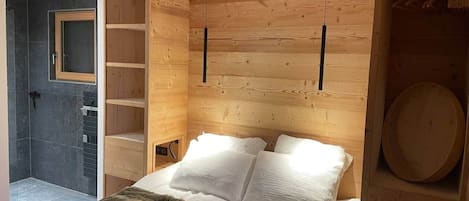 Un dormitorio de madera con cama, estante y un objeto circular en la pared.