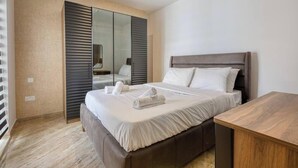 Une chambre d’hôtel avec un lit, une table de chevet en bois, un miroir et un placard à portes coulissantes.
