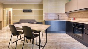 Une cuisine moderne avec un plan de travail en bois, un four encastré et un canapé gris dans l’espace repas.