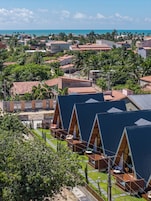 Um resort com várias estruturas em formato de A, uma área de piscina e vista para o oceano.