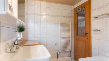 Un baño con un lavamanos blanco, una puerta de madera y un perchero para toallas.