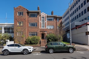 A multi-story building with a brick facade, a garage entrance, and a parking sign indicating a 2-hour parking limit. - Charming Art Deco Unit in East Melbourne (East Melbourne)