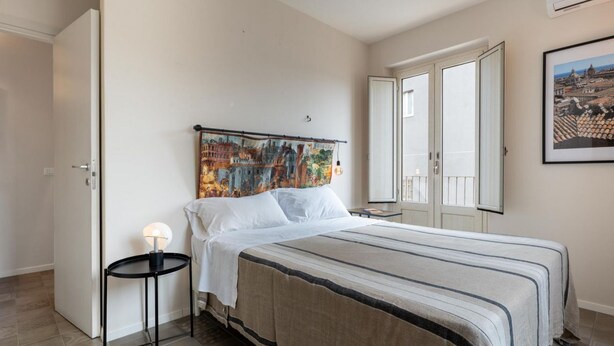 Ein Schlafzimmer mit einem Bett, einem Nachttisch, einem Wandbild und einer Tür.
