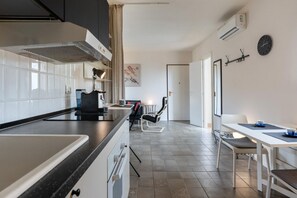 A modern kitchen with a large island, a dining area with a table and chairs, and a visible air conditioning unit. - A modern and welcoming 70-square-meter open space apartment, ideal for three people, located on the first floor of a renovated building with an elevator.The property enjoys a strategic location, just a 20-minute walk from Catania's city center and all it (Catania)