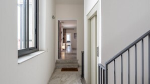 Ein schmaler Flur mit Marmorboden, einer Fußmatte und einer Treppe, die in einen anderen Raum führt.
