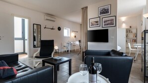 Ein modernes Wohnzimmer mit einer Couch, einem Esstisch und einem an der Wand befestigten Fernseher.