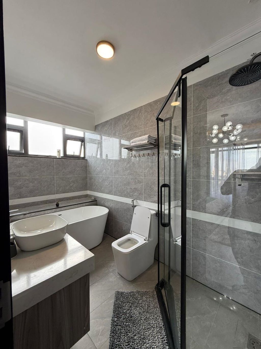 A modern bathroom with a glass shower enclosure, a freestanding bathtub, and a toilet.