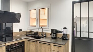 Ett modernt kök med en inbyggd ugn, en kaffebryggare och en mixer.