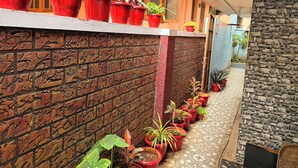A brick wall with potted plants, a stone wall, and a tiled pathway. - Eden Gardens Home Stay (Coimbatore)