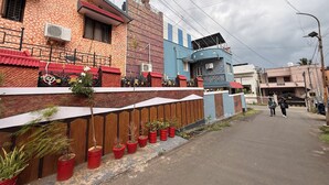 A residential street with houses, a gated entrance, and potted plants along the sidewalk. - Eden Gardens Home Stay (Coimbatore)