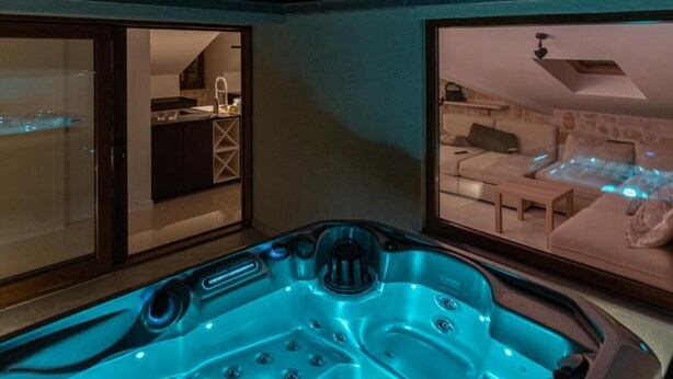 A spa area with a hot tub, a bedroom with a bed and a nightstand, and a bathroom with a sink and mirror. - Cozy modern apartment with a hot tub in a stone house in the heart of Omiš. (Omiš)