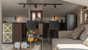 A modern kitchen with a dining area, a sofa, and a coffee table with a fruit bowl and glasses. - Cozy modern apartment with a hot tub in a stone house in the heart of Omiš. (Omiš)