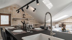 A modern kitchen with a large island, built-in oven, and pendant lighting. - Cozy modern apartment with a hot tub in a stone house in the heart of Omiš. (Omiš)