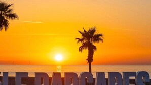 Une scène de plage avec une pancarte indiquant « BARCARES » et des palmiers.