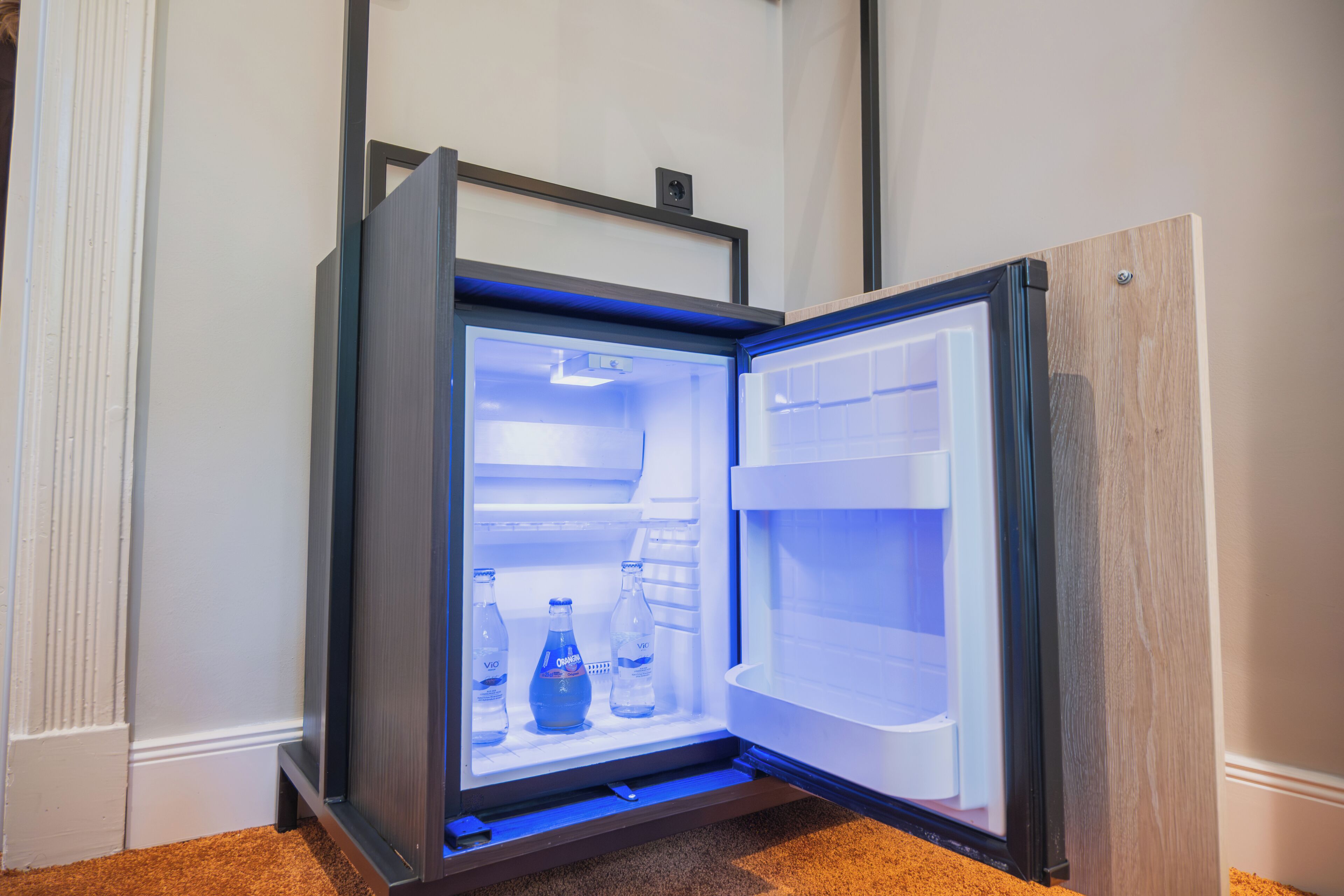 An open refrigerator with a wooden frame, a shelf with bottles, and a door with a handle.
