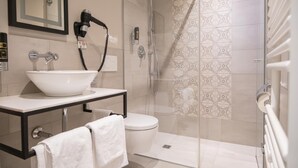 A modern bathroom with a glass shower enclosure, a white sink with a large basin, and a toilet. - Hotel Villa Nord (Hamburg)