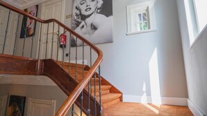 A staircase with wooden railings and carpeted steps, a fire extinguisher, and a framed picture on the wall. - Hotel Villa Nord (Hamburg)