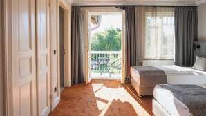 A bedroom with a balcony, a bed, a sofa, and a window with curtains. - Hotel Villa Nord (Hamburg)