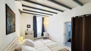 A bedroom with a bed, a bedside table, a lamp, a window with curtains, and a door. - Bright city centre apartment - 3 guests (Fouras)