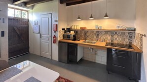 Una cocina compacta con techo de madera, salpicadero de azulejos e iluminación colgante.