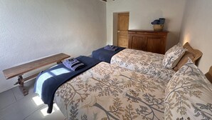 Un dormitorio con cama, un banco, un armario de madera y una puerta.
