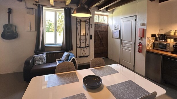Una habitación acogedora con una mesa de comedor, un sofá, una guitarra y una cocina equipada.