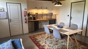 Cocina compacta con comedor, equipada con cafetera, tostadora y refrigerador pequeño.