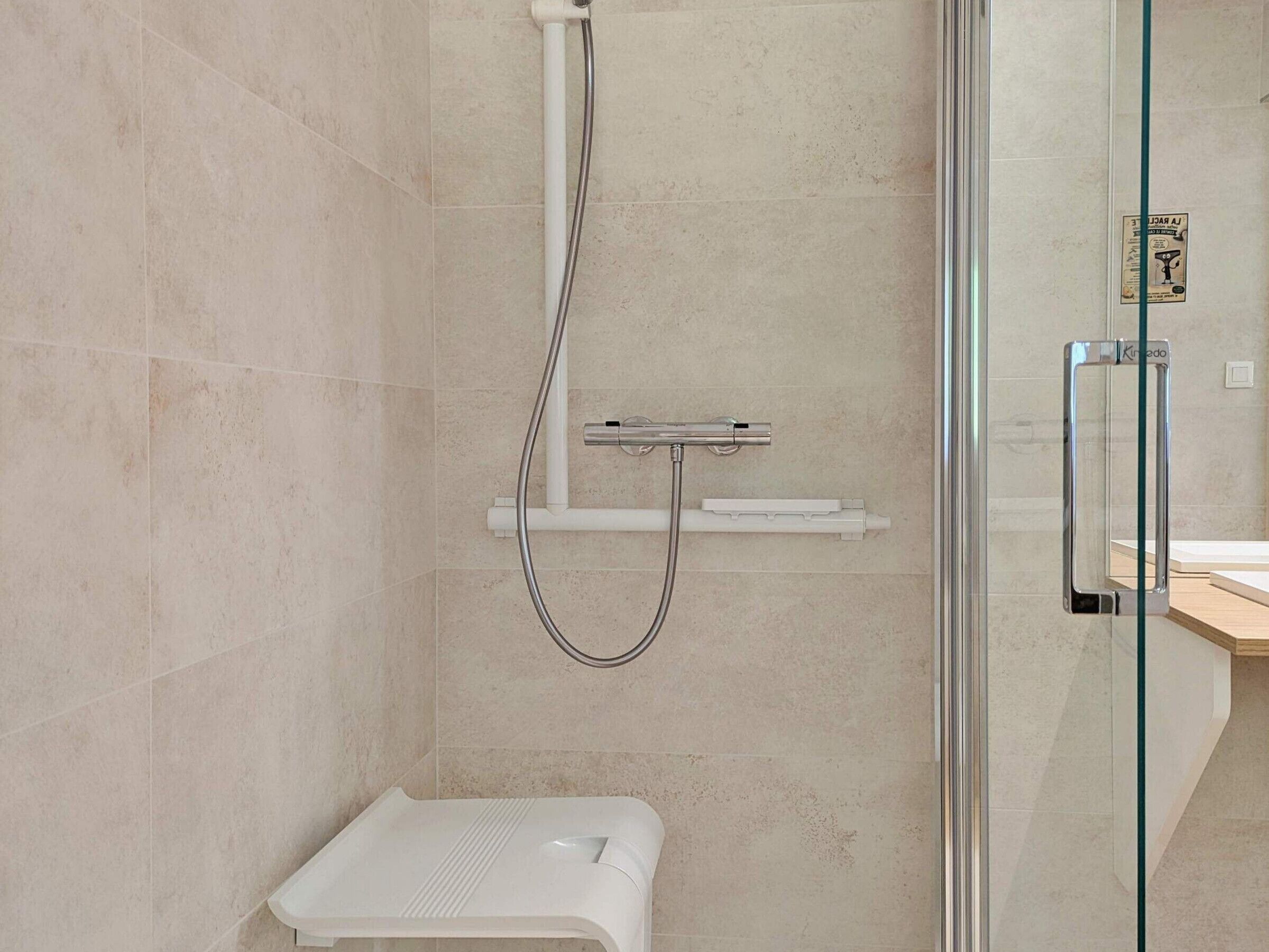 Un baño moderno con cabina de ducha de vidrio, un inodoro blanco y un estante pequeño.