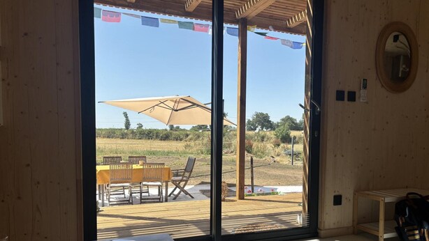 A wooden interior with a sliding glass door leading to an outdoor deck with a table and chairs.