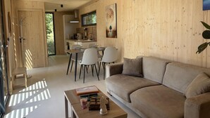 A modern interior with a wooden floor, a sofa, a dining table with chairs, and an air conditioning unit.