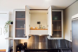 A kitchen with open cabinets, a stainless steel range hood, and a coffee maker. - Providencia Moderno 2D 5 huespedes (Providencia)