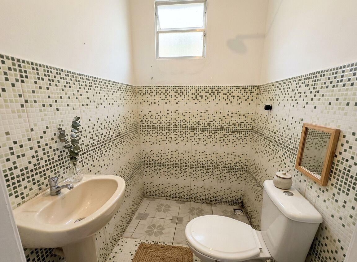 A bathroom with a sink, toilet, and a small window.