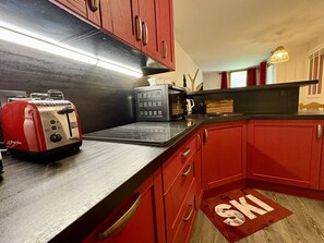 Eine Küche mit roten Schränken, einem Toaster, einer Mikrowelle und einem Wasserkocher.