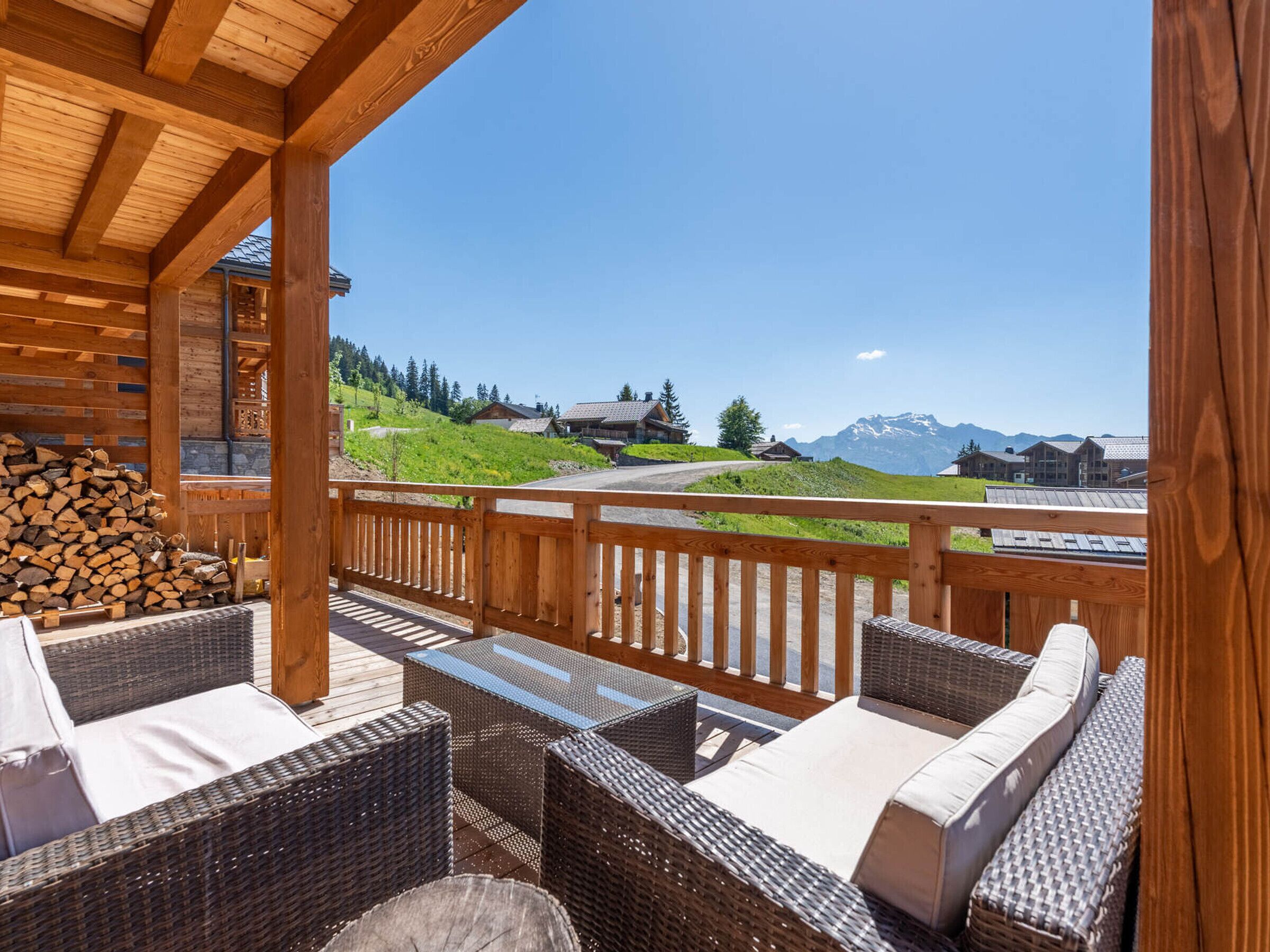 Eine Holzterrasse mit Korbmöbeln und Blick auf eine Berglandschaft.