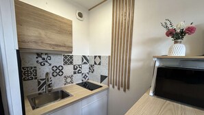 Une cuisine compacte dotée d’un plan de travail en bois, d’un évier et de carreaux décoratifs sur la crédence.