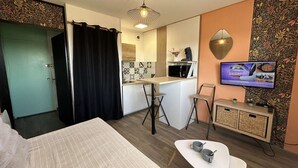 Une chambre d’hôtel équipée d’un lit, d’un bureau, d’une petite kitchenette, d’une télévision et d’un coin salon.