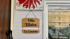 A wooden sign with 'Villa Kilalex La Landaise' hanging on a white wall.