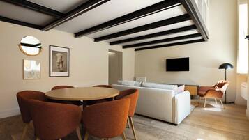 A modern living room with a round wooden table, orange chairs, a sofa, and a TV mounted on the wall.