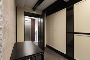 Un pasillo con una mesa negra, un armario con espejo y una puerta que da a otra habitación.